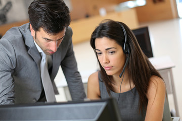 Sales representative with manager in front of desktop