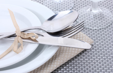 White empty plates, fork and knife tied with a ribbon and