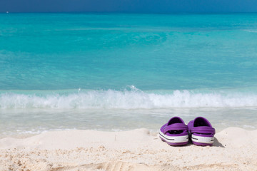 Pair of colored sandals on a white sand beach