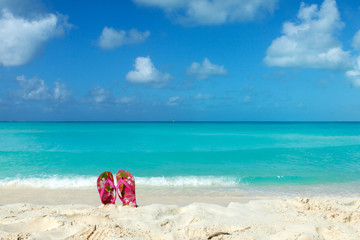 Fototapeta na wymiar Pair of colored sandals on a white sand beach