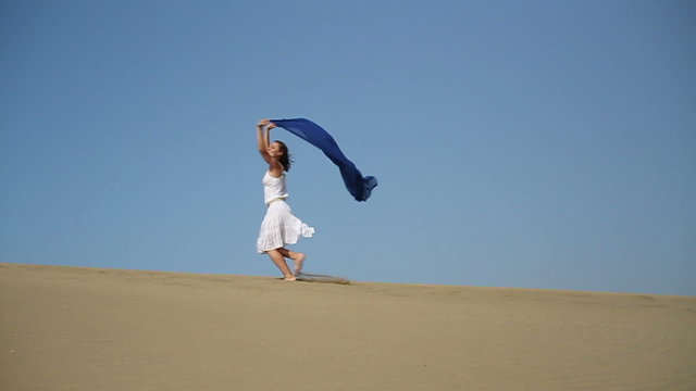 Woman with waving sarong running in the desert, slow motion