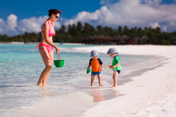 Fototapeta na wymiar Mother and twin boys playing on the beach