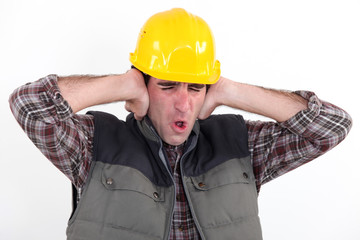 A construction worker covering his ears.