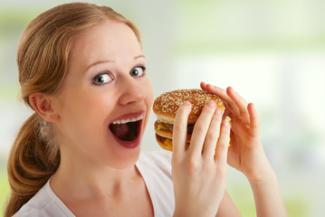 attractive young  woman eats unhealthy food, hamburger