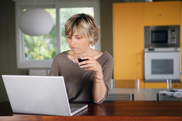 Woman working on her laptop while drinking a cup of coffee