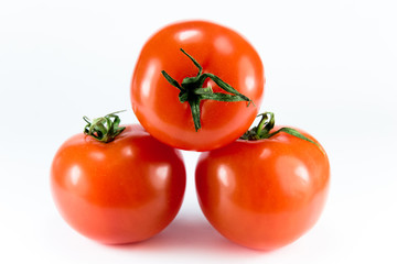 Three stacked ripe tomatoes on a white background