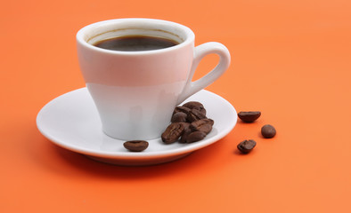 Classic white coffee cup with saucer isolated on orange
