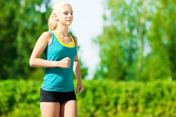 Fototapeta premium Young woman running in green park