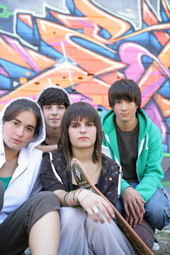 Group of teenagers sitting in front of a graffiti wall
