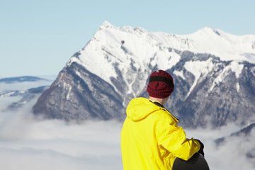 Fototapeta na wymiar Teenage Snowboarder Admiring Mountain View Whilst On Ski Holiday