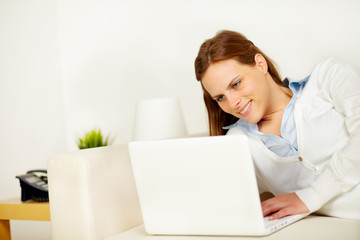 Cheerful woman lying on sofa with a laptop