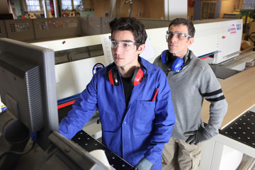 Young intern operating factory saw
