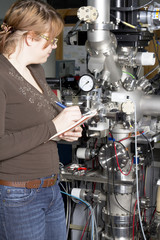 Young scientist inspects the electronic parts of ION accelerator - obrazy, fototapety, plakaty