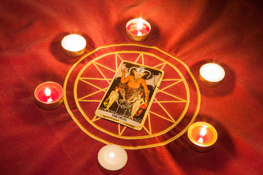 The Devil, tarot card illuminated by candlelight.
