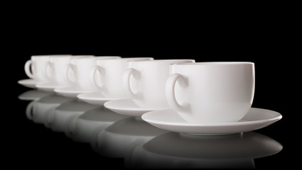 White cups and saucers on a black background