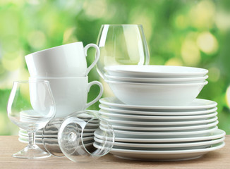 Clean dishes on wooden table on green background