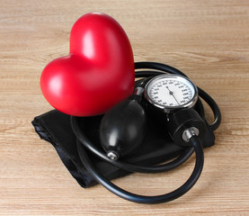 Black tonometer and heart on wooden background