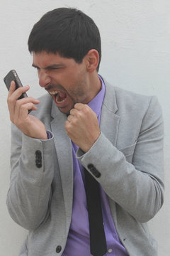 An angry businessman is shouting at his mobile phone