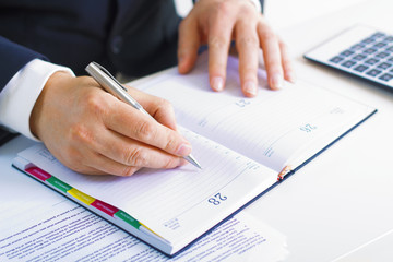 Business man in dark suit writing on his datebook