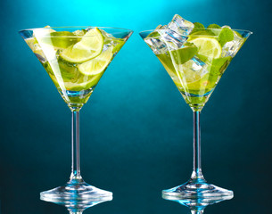 glasses of cocktails with lime and mint on blue background