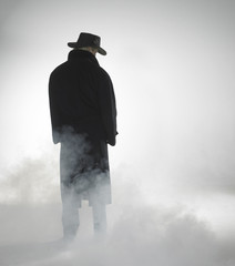 Woman wearing trench coat and standing in fog