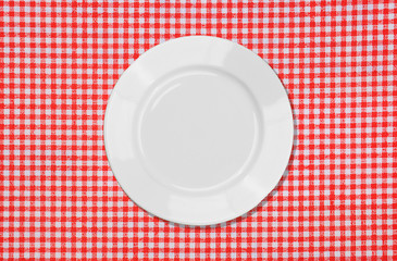 White plate on red and white tablecloth