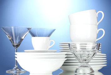 empty bowls, plates, cups and glasses on blue background