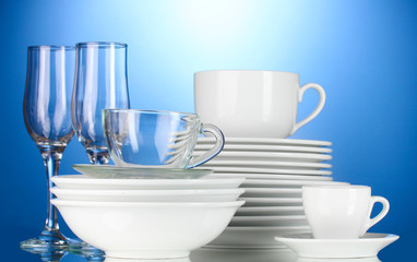 empty bowls, plates, cups and glasses on blue background