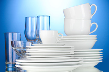 empty bowls, plates, cups and glasses on blue background