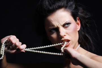 Frau beisst wütend in eine Perlenkette