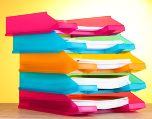 bright paper trays on wooden table on yellow background