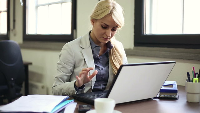 Businesswoman finishing work on laptop and smiling to camera
