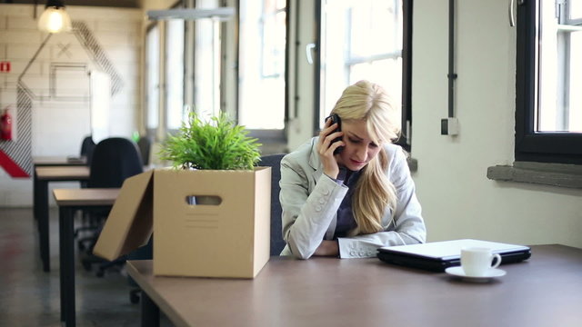 Just fired, sad businesswoman talking on cellphone in the office