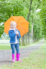 Obraz premium little girl with umbrella in spring alley