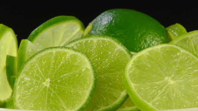 sliced limes close up rotating on black background