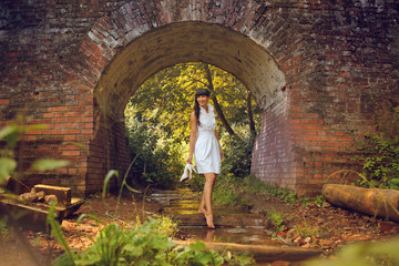 Fototapeta na wymiar young woman standing in the water against a brick arch