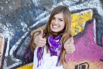 Style teen girl near graffiti wall.