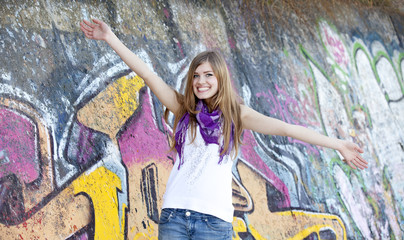 Style teen girl near graffiti wall.