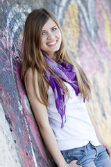 Style teen girl near graffiti wall.