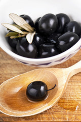 Olives on the wooden table on a white plate