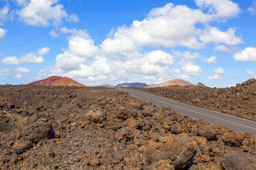 Road through lava rocks and volcanic mountains. Los Hervideros.