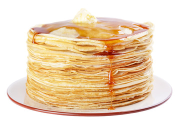 A stack of thin pancakes with honey and butter