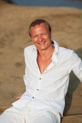 Beautiful man having rest on river beach. Outdoor shot