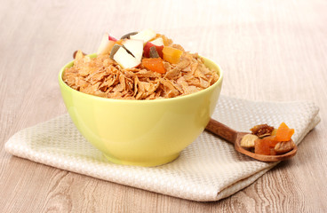 tasty cornflakes in bowl with dried fruits on wooden table