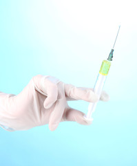 Syringe in hand on blue background