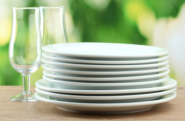 Clean dishes on wooden table on green background