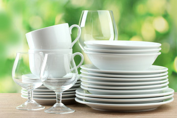 Clean dishes on wooden table on green background