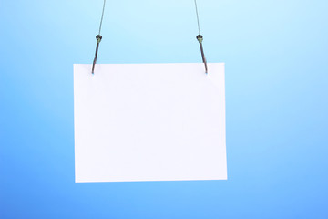 Empty sheet of a paper on fish hooks on blue background