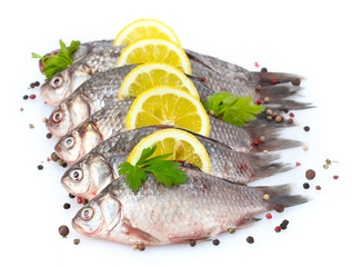 Fresh fishes with lemon, parsley and spice isolated on white