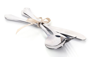 Silver fork, spoon and knife tied with ribbon isolated on white